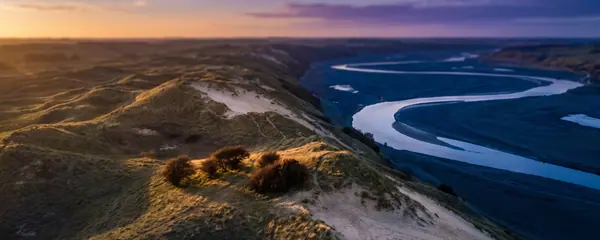 Sand hills above a winding river valley at dusk